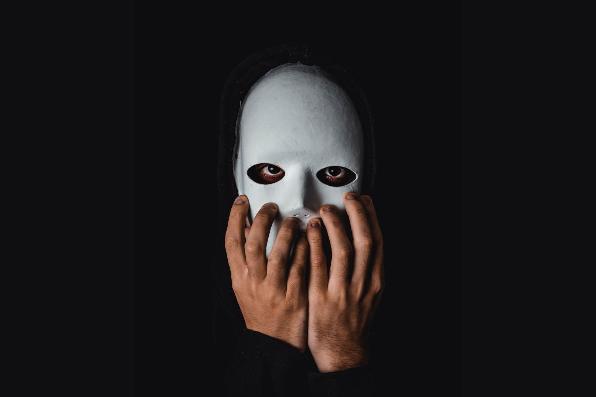 man with white mask on touching his face.